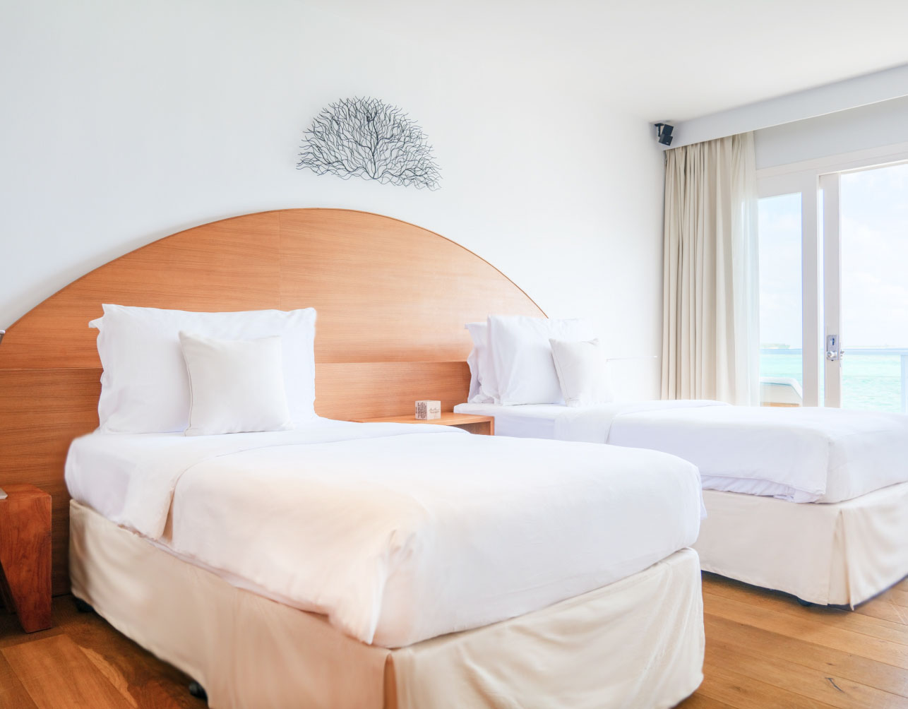 A bedroom with 2 single beds of the bedrooms inside of our Maldives Family Villas.