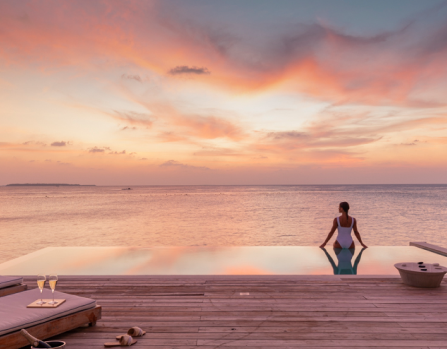A woman relaxing and enjoying the ocean view from the freshwater pool at our Sunset Water Villa Maldives.